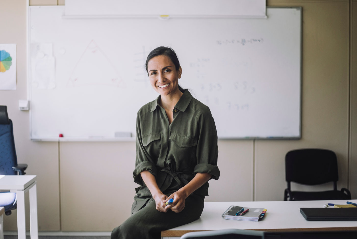 Smiling woman in a green shirt with a classroom in the background
