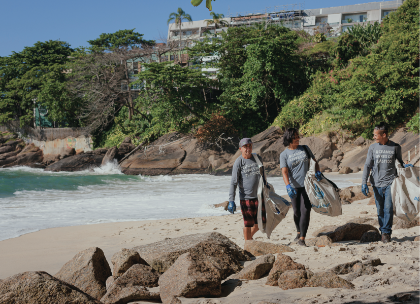 A group of people on a beach carrying rubbish bags