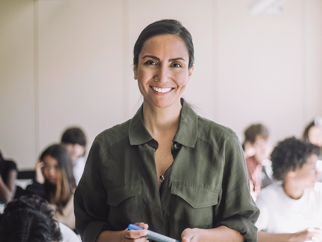 Smiling woman in a green shirt with a blackboard in the background