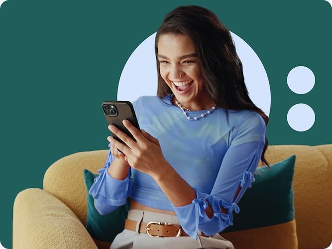 A smiling woman with a phone sitting on a sofa