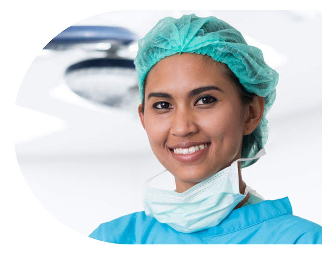 An image of a smiling surgeon wearing surgical scrubs in the operating room.