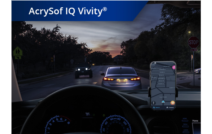 Blick aus einem Auto heraus auf eine Straße in der Dämmerung. Ein Smartphone ist auf dem Armaturenbrett befestigt. Der weiße Text links oben besagt “AcrySof IQ Vivity”. 