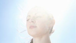 Eine Frau, die die Augen geschlossen hat, mit der Sonne, die auf ihren Hinterkopf scheint.