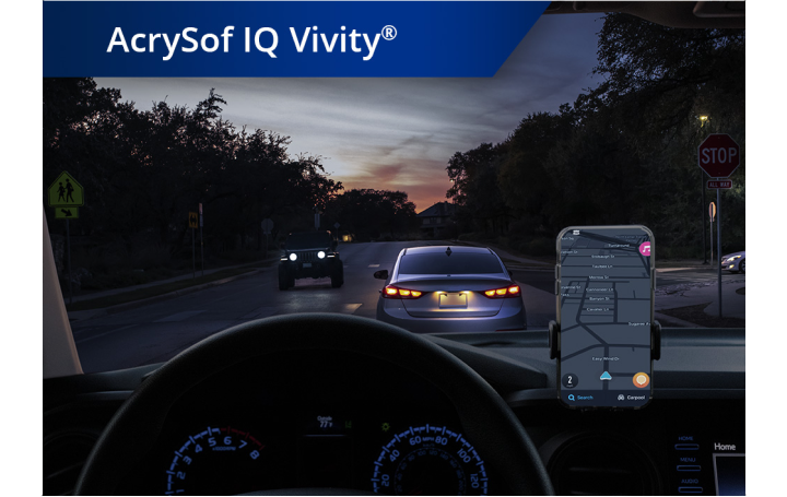 Blick aus einem Auto heraus auf eine Straße in der Dämmerung. Ein Smartphone ist auf dem Armaturenbrett befestigt. Der weiße Text links oben besagt “AcrySof IQ Vivity”.