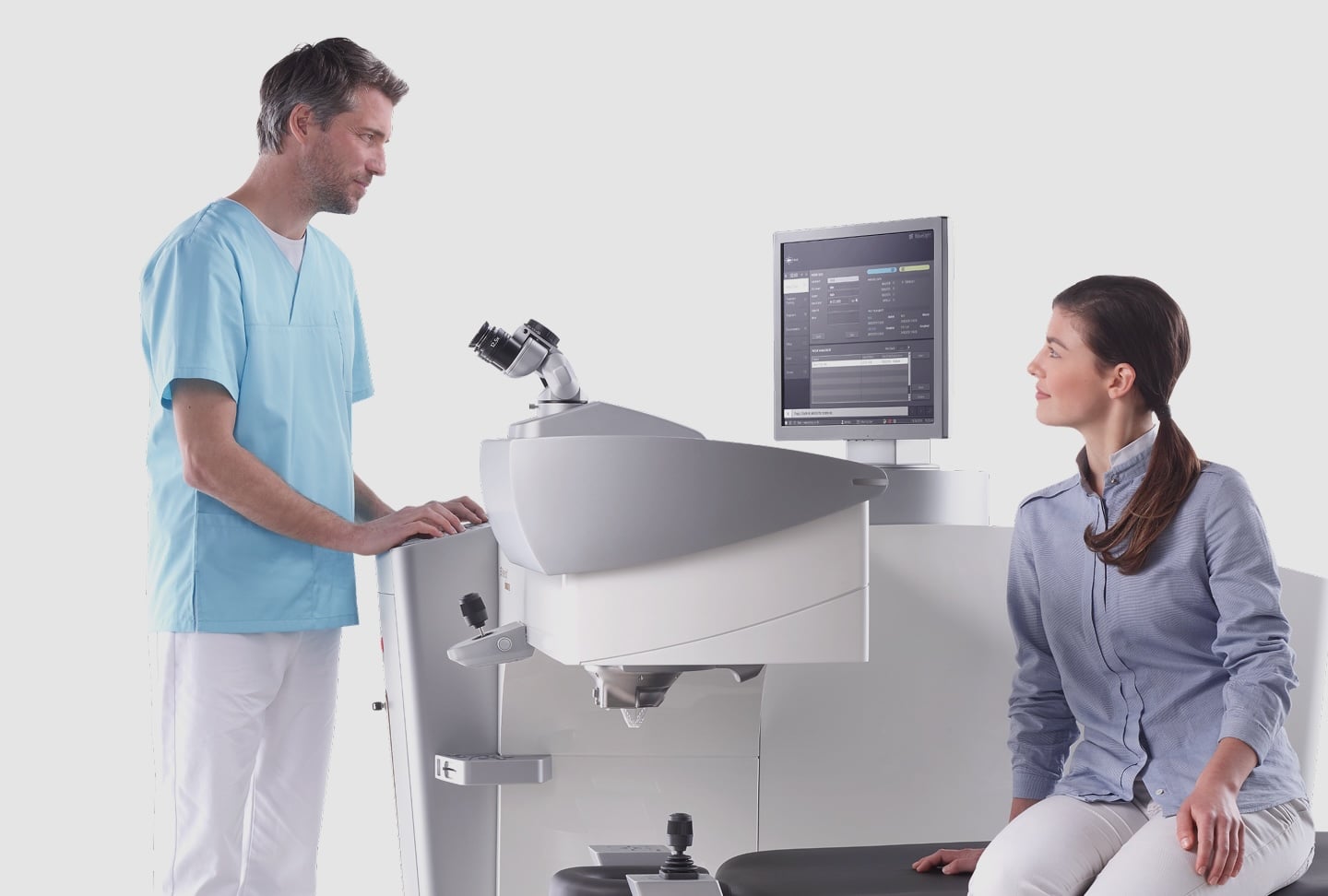 Augenfachkraft bedient ein Wavelight Plus Laser-Augenoperationssystem, während ein Patient während der Beratung daneben sitzt