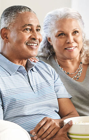 Older couple smiling and watching TV