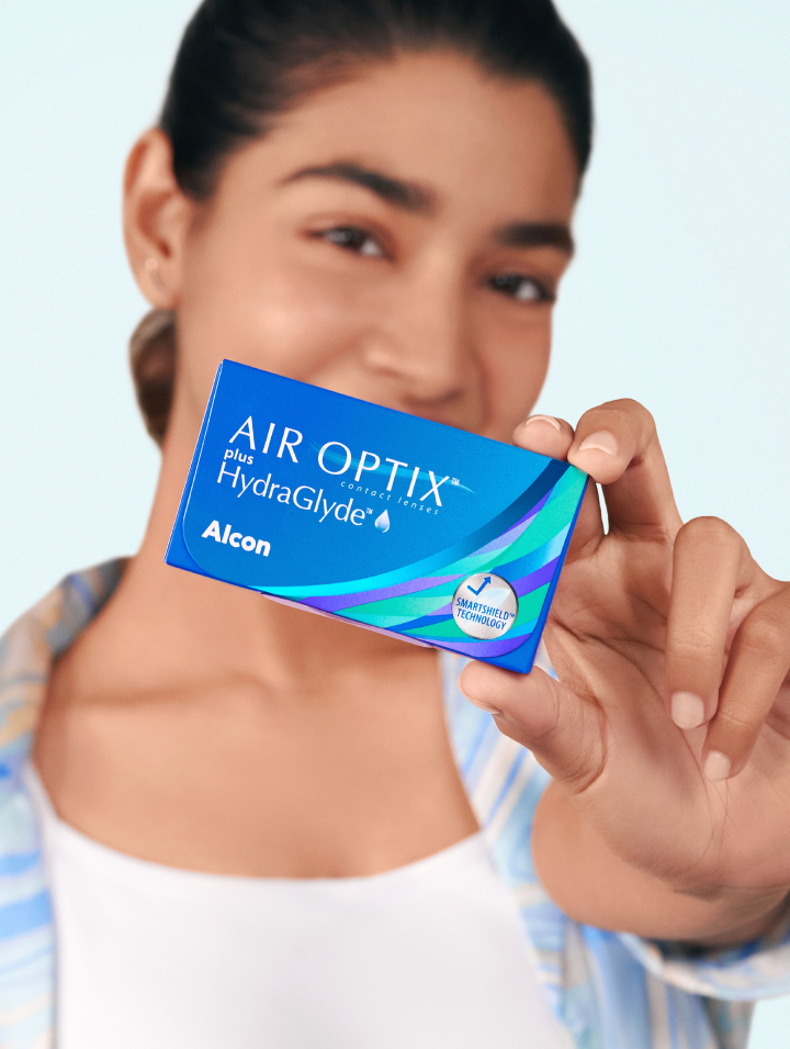 Woman holding AIR OPTIX™ Plus HydraGlyde monthly replacement contact lenses