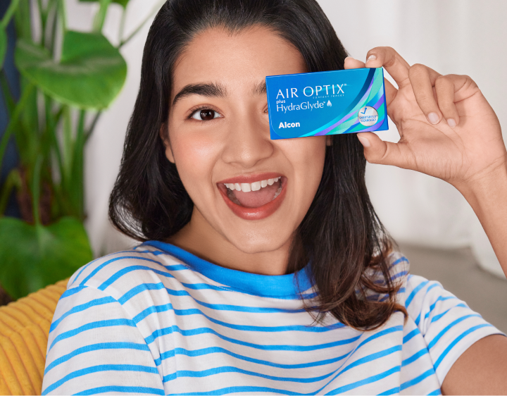 Smiling woman with a pack of Air optix plus HydraGlyde