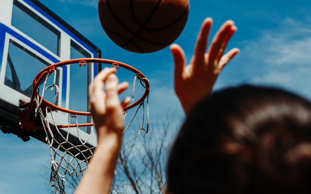 Woman shooting a basketball into a basketball hoop