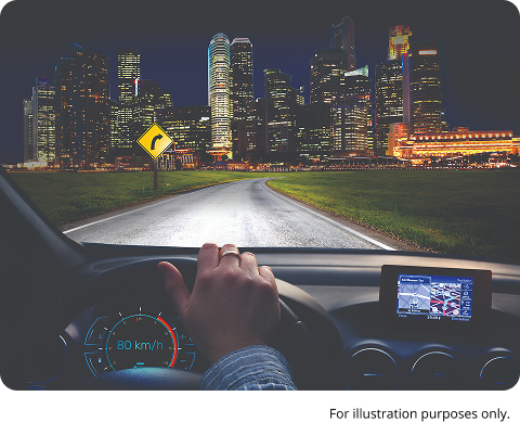 View from inside a car driving at night toward a lit city skyline, with dashboard and navigation screen visible