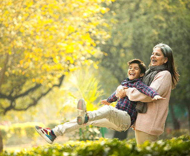 Grandmother playing with her grandson outdoors in a park on a sunny day