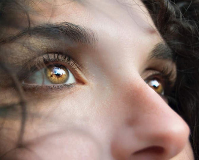 Close-up of a person’s eyes looking upward, highlighting clear vision and detailed reflections in the irises.