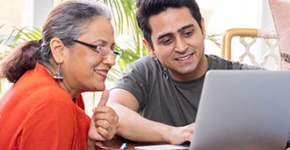 Two smiling people checking something on the computer