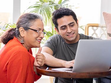 Two smiling people checking something on the computer
