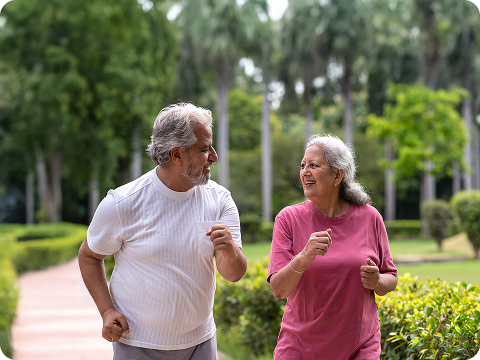 Older couple jogging together on a park path and smiling at each other