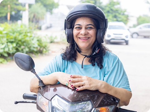 Woman wearing a helmet while sitting on a scooter and smiling at the camera