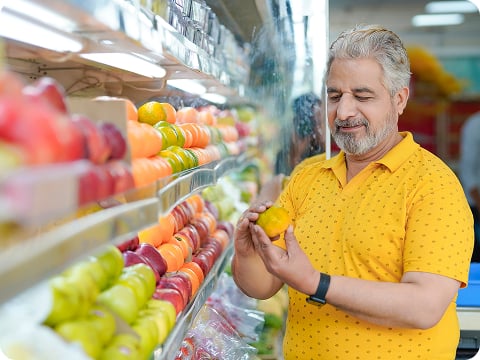Older man selecting fresh fruit while shopping in a grocery store