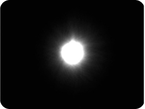 Sfondo nero con una luce luminosa al centro che rappresenta la misurazione dell'alone del banco ottico per la IOL monofocale AcrySof® IQ.