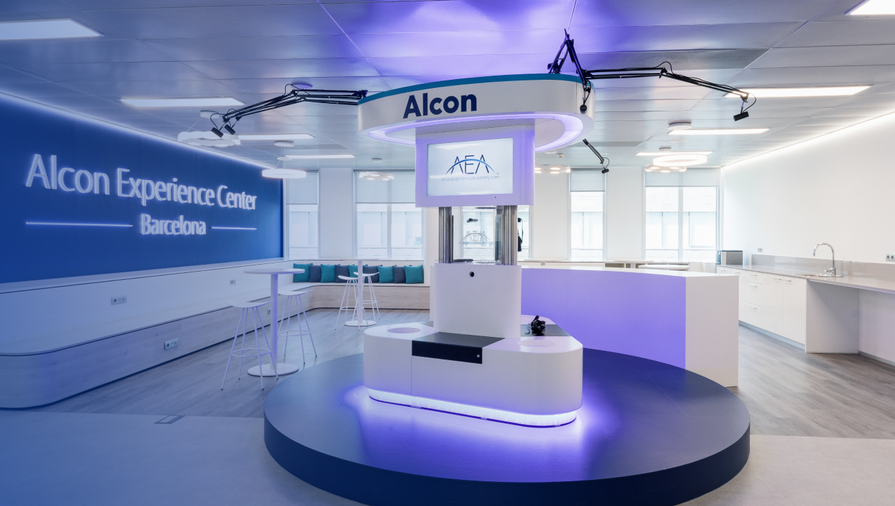 Interni moderni dell’Alcon Experience Center di Barcellona, con area espositiva centrale AEA, sedute e uno spazio aperto luminoso per workshop e formazione.