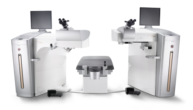 Sistema wavelight refractive suite composto da due laser oftalmici con microscopi e monitor, collegati da un lettino per il paziente.