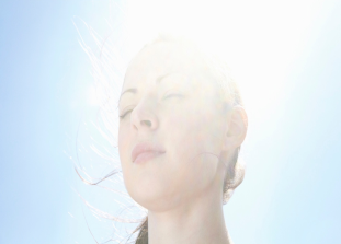 後頭部に陽光を浴びながら遠くを見つめる女性の画像