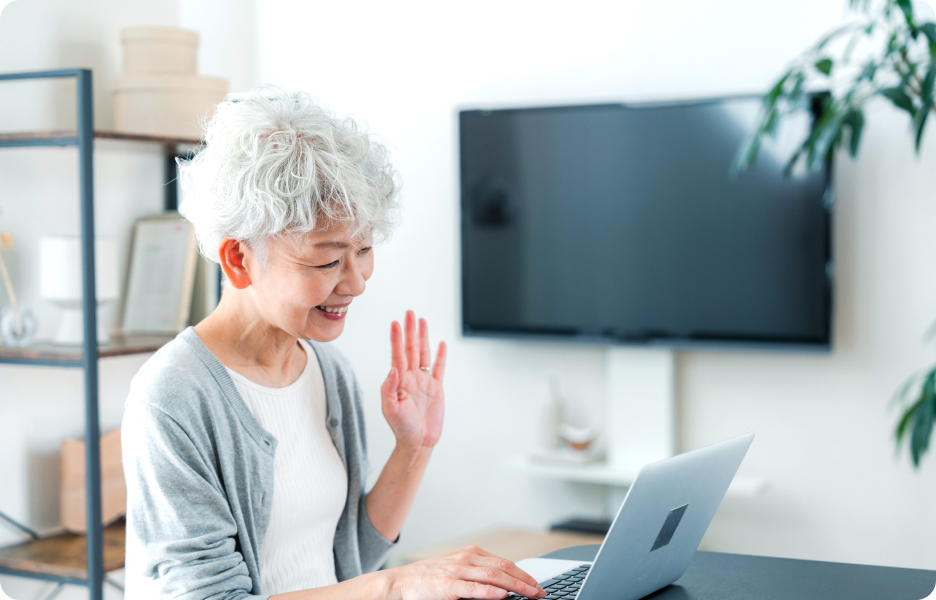 An elderly woman talking through a laptop.