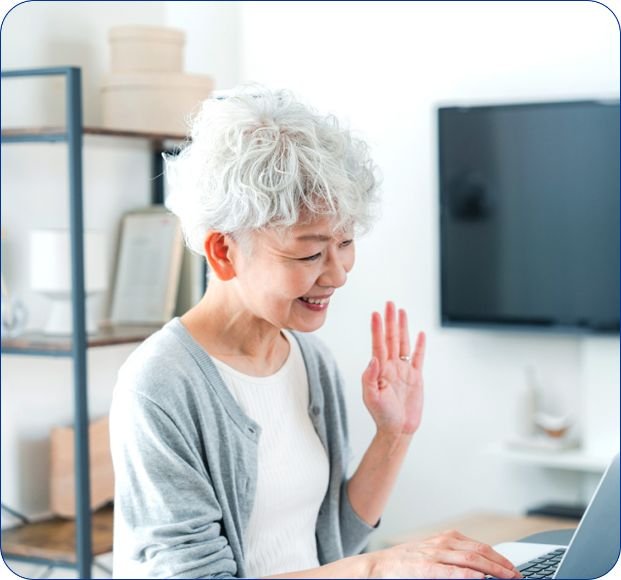 ご年配女性がパソコンを開いて、ビデオ通話している