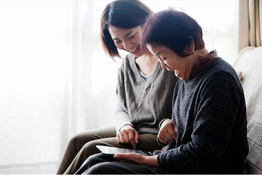 親子がソファに座って、一緒にタブレットを見ながら操作する
