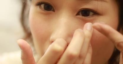 Close-up of a woman inserting a contact lens