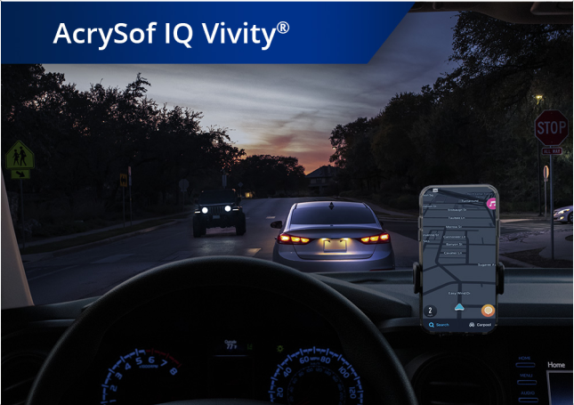 Un coche en una carretera con condiciones de poca luz con un teléfono montado en el salpicadero. Aparece un texto blanco en la esquina superior izquierda de esta imagen que dice: “AcrySof IQ Vivity.”