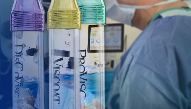 A close-up shot of three tubes of Alcon Ophthalmic Viscosurgical Devices. The tube with the purple cap is labeled DisCoVisc, the tube with the yellow cap is labelled VISCOAT, and the tube with the green cap is labelled PROVISC. Behind the tubes there is a surgeon wearing a medical mask and surgical scrubs.