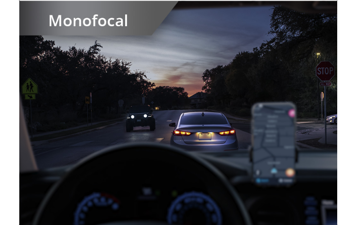 Carro na estrada em condições de fraca luminosidade com um telemóvel instalado no painel de instrumentos. O texto a branco no canto superior esquerdo desta imagem diz "Monofocal".