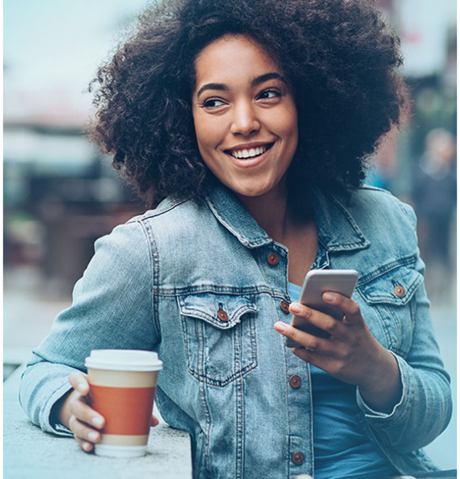 Woman smiling with mobile phone and cup