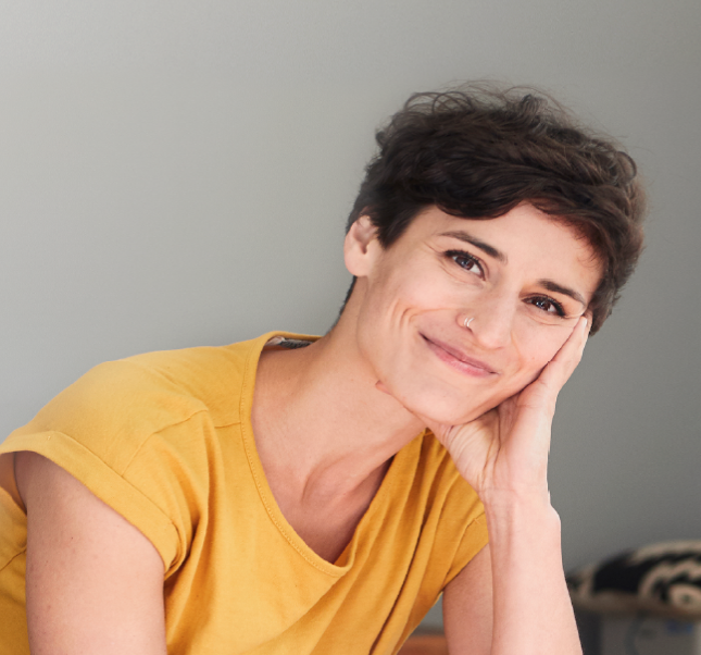 Woman with yellow shirt smiling looking directly at camera