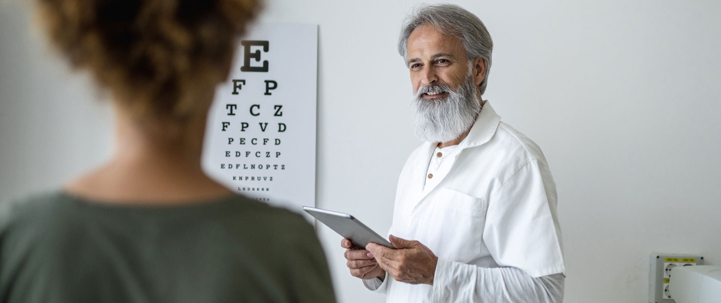 Woman reading eye chart as part of a vision exam with eye doctor.