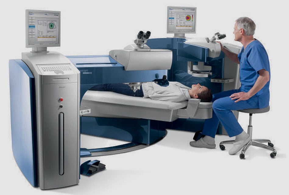 Eye care professional operating a wavelight plus laser eye surgery system while a patient sits nearby during a consultation