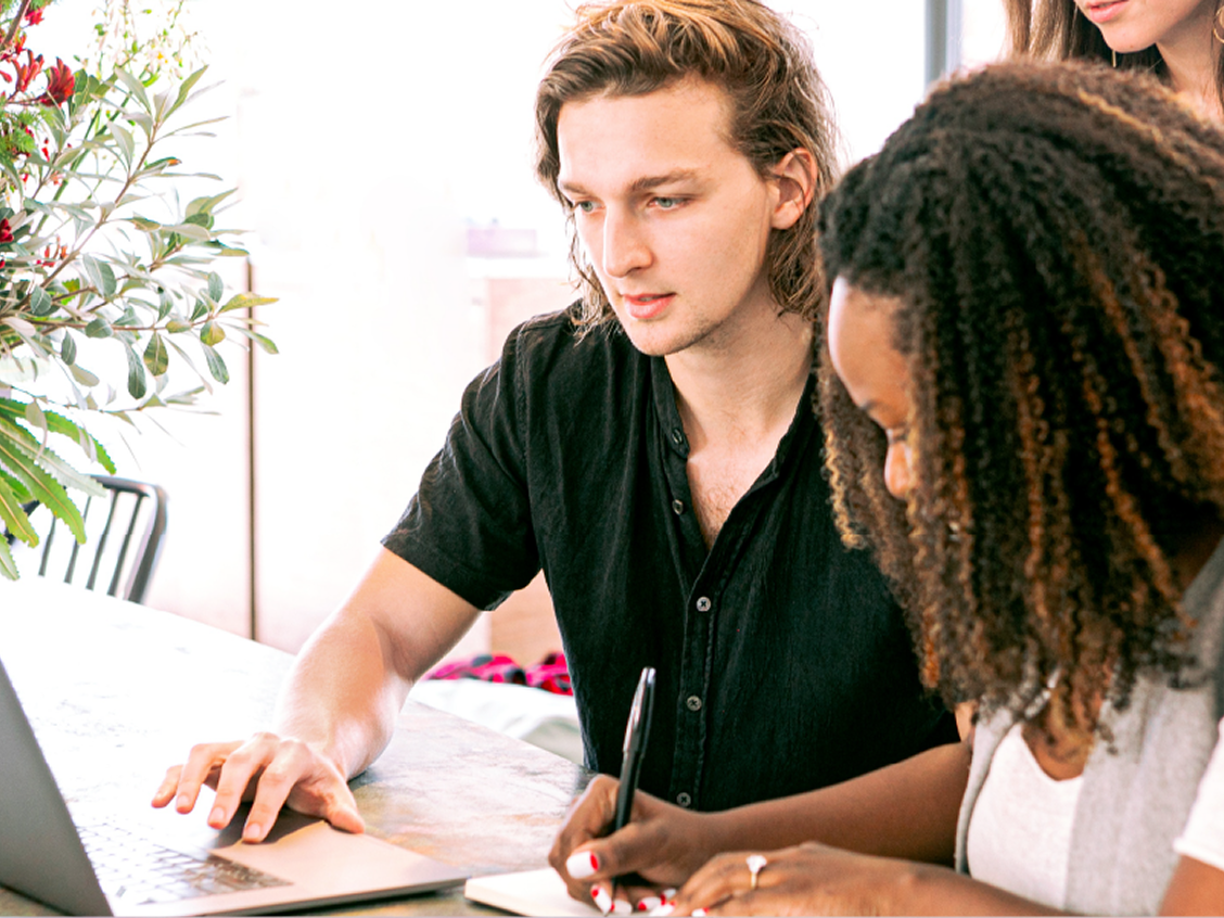Two people at a desk with a laptop
