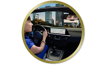 Woman driving a car through the city, looking ahead with her reflection visible in the rearview mirror