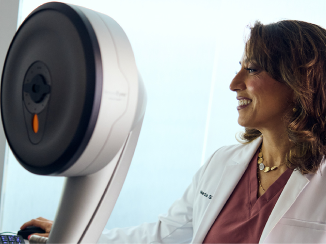 A Doctor in white lab coat standing beside advanced eye care equipment, preparing for a refractive wavelight surgery procedure.