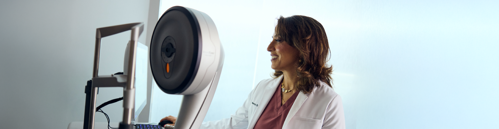 A Doctor in white lab coat standing beside advanced eye care equipment, preparing for a refractive wavelight surgery procedure.