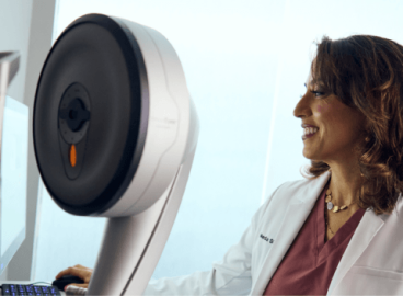 A Doctor in white lab coat standing beside advanced eye care equipment, preparing for a refractive wavelight surgery procedure.