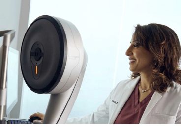A Doctor in white lab coat standing beside advanced eye care equipment, preparing for a refractive wavelight surgery procedure.