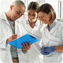 A team of healthcare workers collaborates and reviews notes on a clipboard.