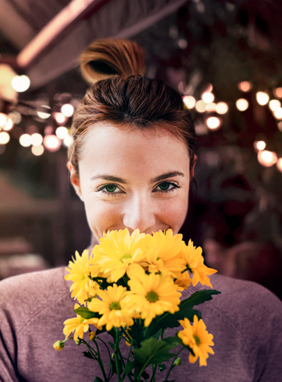 A smiling woman holds a bouquet of yellow flowers