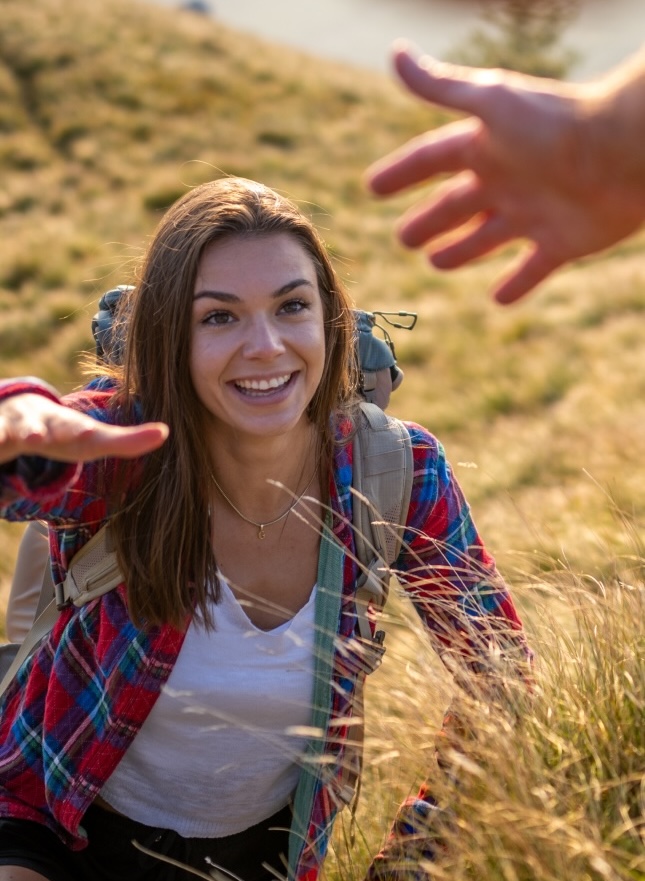 A woman reaching for another person's hand during a climb