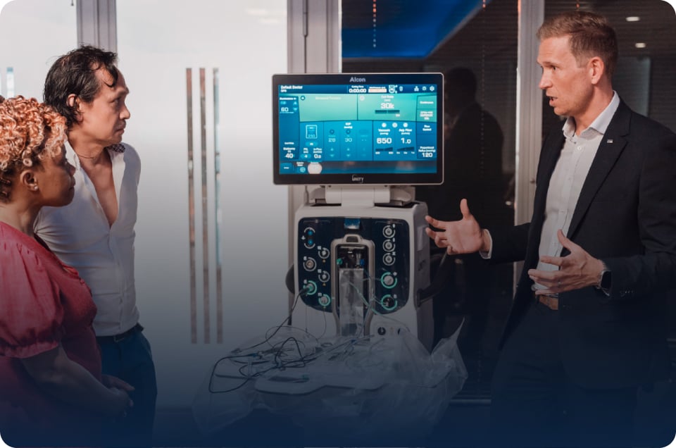Demonstration of an Alcon medical system with touchscreen display and control console in a clinical environment.