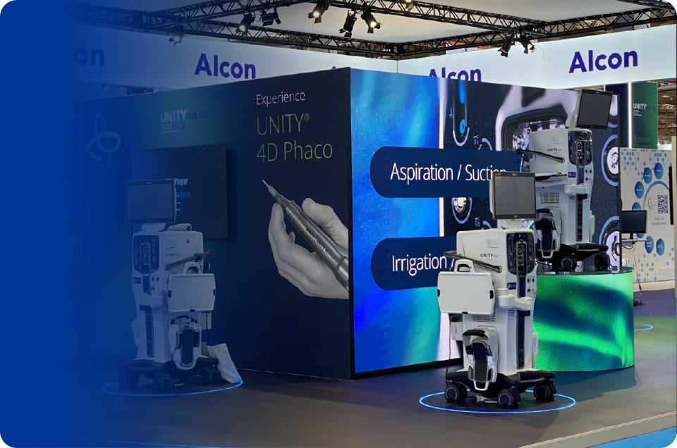 Alcon exhibition booth featuring UNITY 4D Phaco ophthalmic surgical systems and digital display screens.
