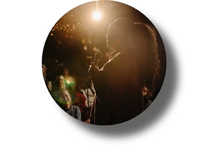 Person on stage under bright spotlight with surrounding darkness, illustrating contrast and light intensity in low-light environments