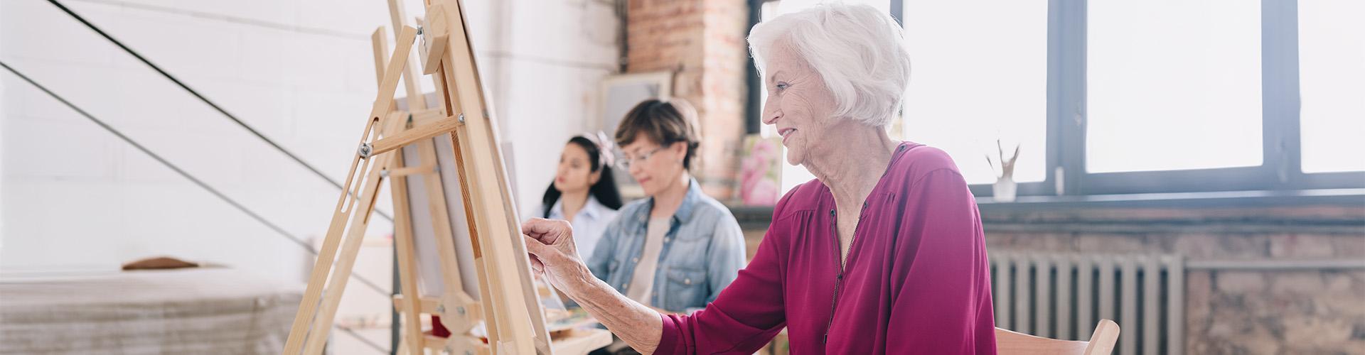 Elderly woman painting a picture