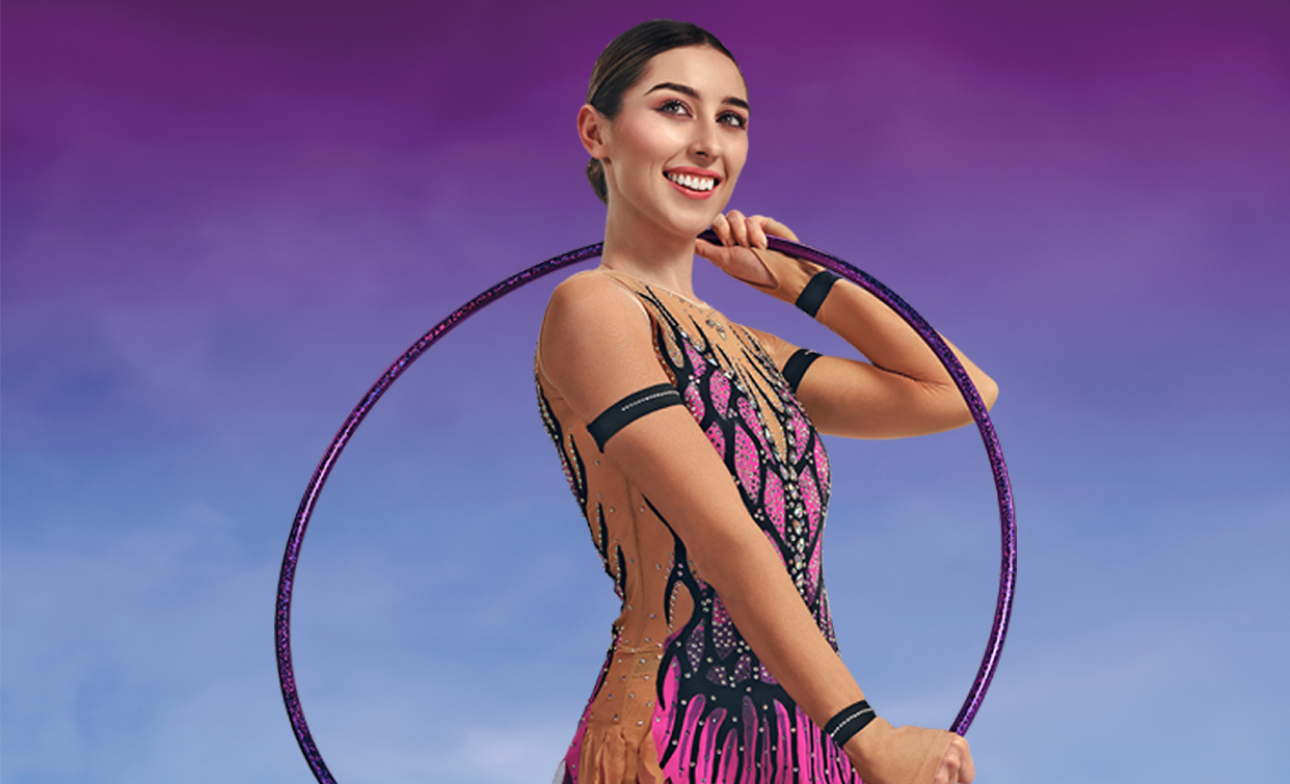 young woman smiling holding a hula hoop across her body while wearing a pink and black sequin dress